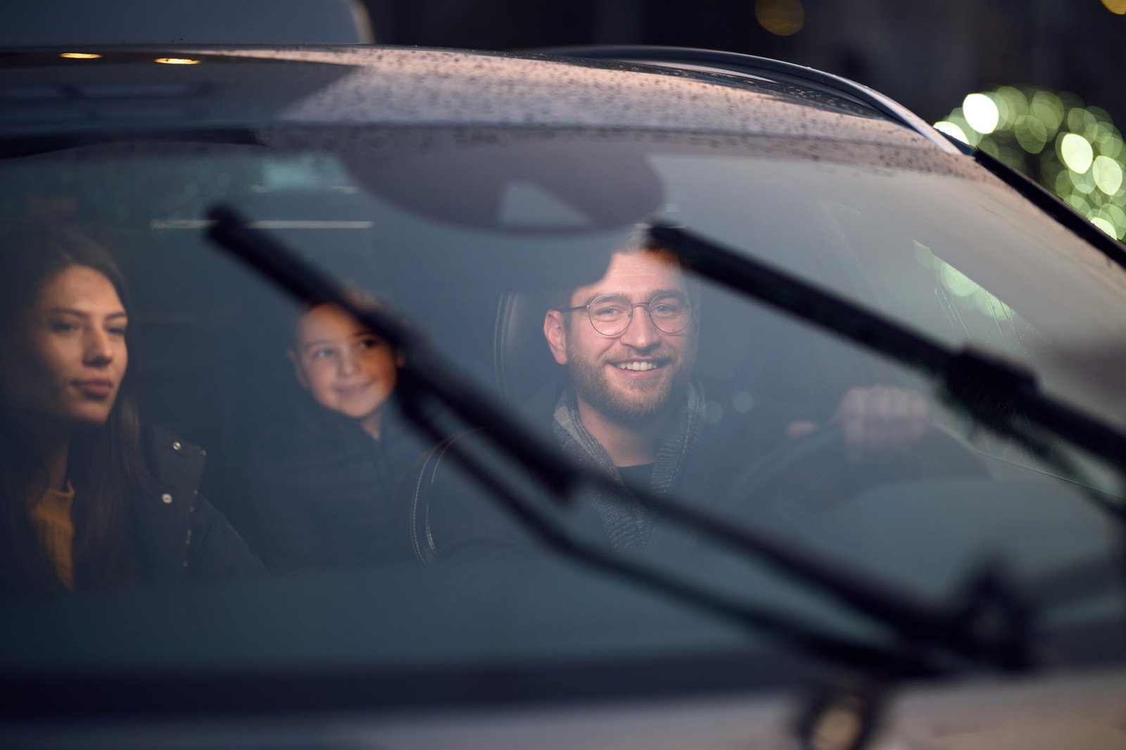 In the nighttime hours, a happy family enjoys playful moments together inside a car as they journey on a nocturnal road trip, illuminated by the glow of headlights and filled with laughter and joy.